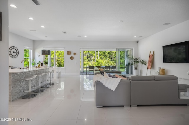 tiled living room featuring plenty of natural light and sink