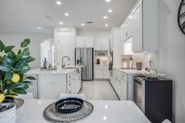 kitchen featuring white cabinetry, sink, decorative backsplash, a kitchen island with sink, and stainless steel fridge with ice dispenser