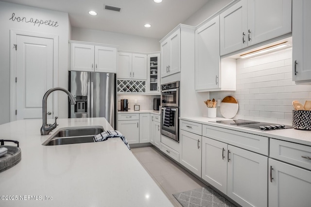 kitchen with white cabinetry, sink, decorative backsplash, and stainless steel appliances