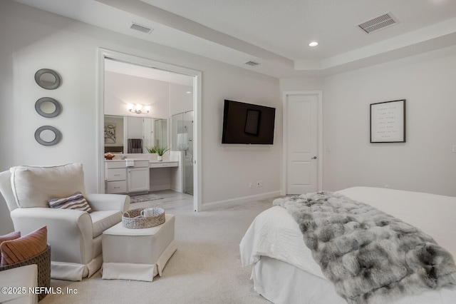 bedroom featuring light carpet, a raised ceiling, and ensuite bathroom