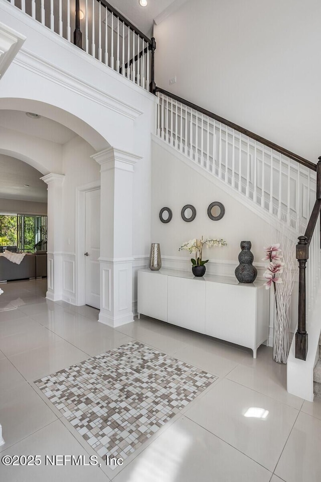 entryway featuring tile patterned floors, a high ceiling, and ornate columns