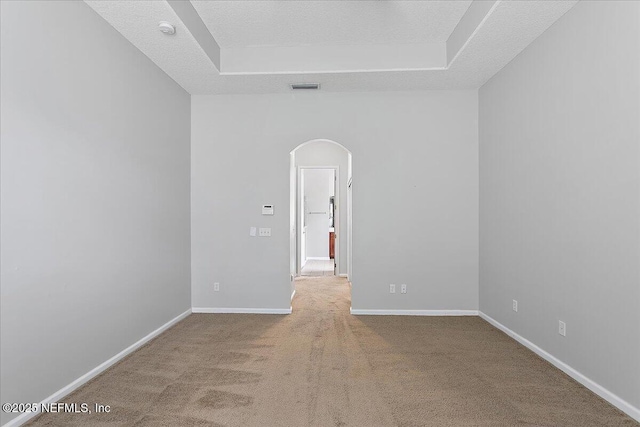 empty room featuring baseboards, visible vents, arched walkways, a textured ceiling, and carpet flooring