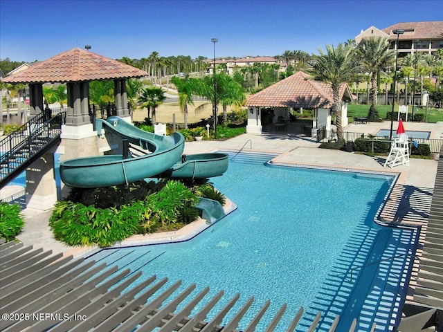 community pool featuring a water slide, a patio area, fence, and a gazebo