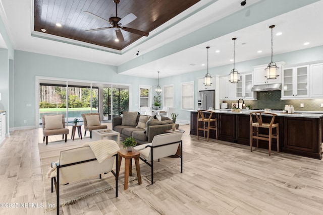 living room with wood ceiling, ceiling fan, a raised ceiling, and light hardwood / wood-style flooring