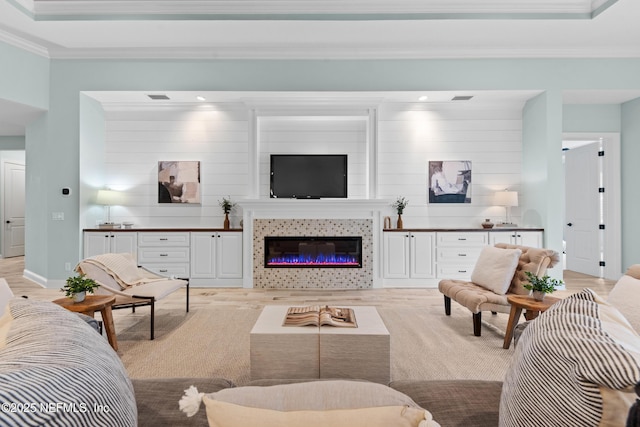 living room with a tray ceiling, crown molding, and light wood-type flooring