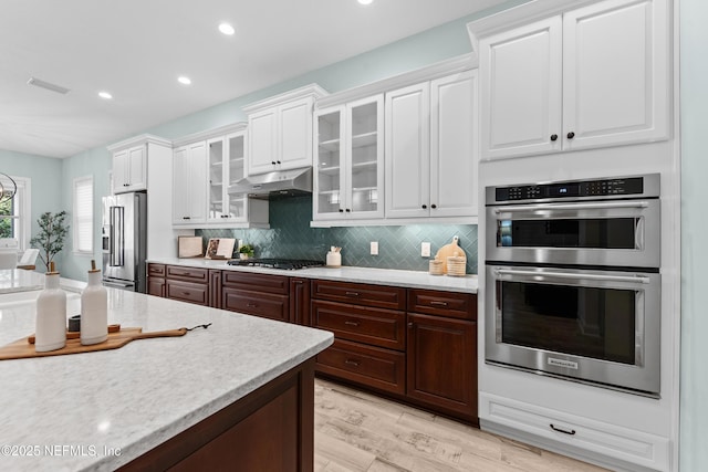 kitchen featuring backsplash, stainless steel appliances, dark brown cabinetry, light hardwood / wood-style floors, and white cabinets