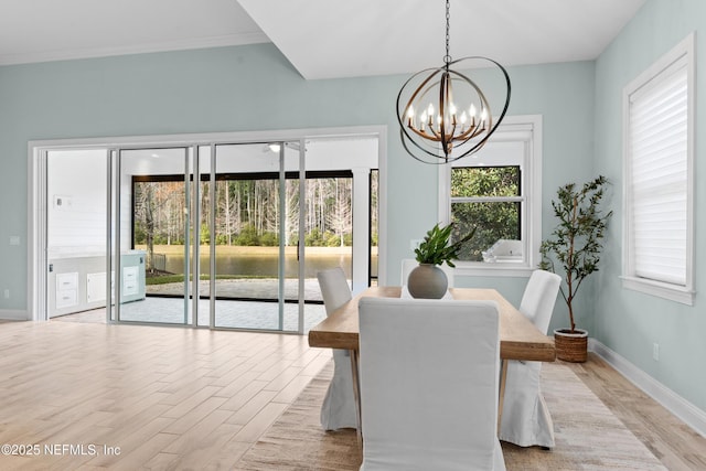 dining space featuring crown molding, a chandelier, light hardwood / wood-style floors, and a wealth of natural light