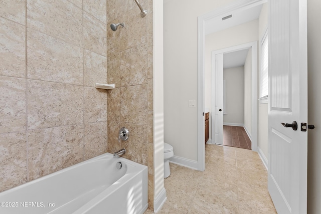 bathroom featuring toilet, tiled shower / bath combo, and tile patterned flooring