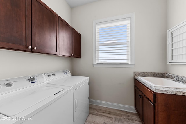 washroom featuring cabinets, separate washer and dryer, sink, and light hardwood / wood-style floors