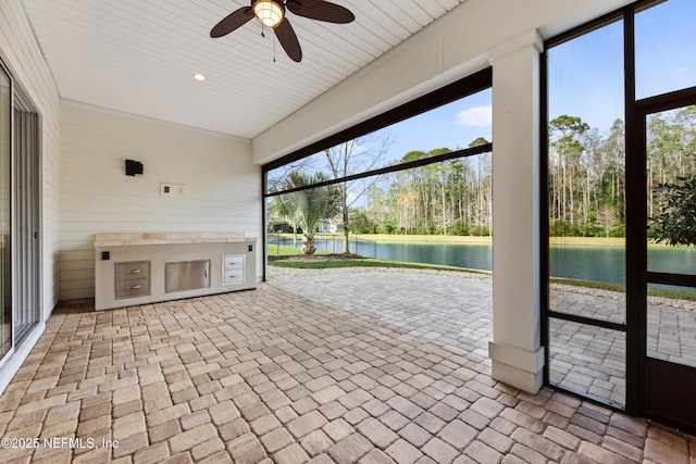 unfurnished sunroom with a water view and ceiling fan