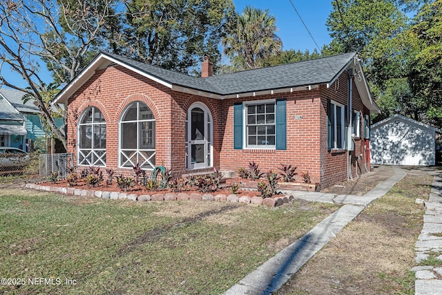 view of front facade featuring a front yard, a garage, and an outdoor structure