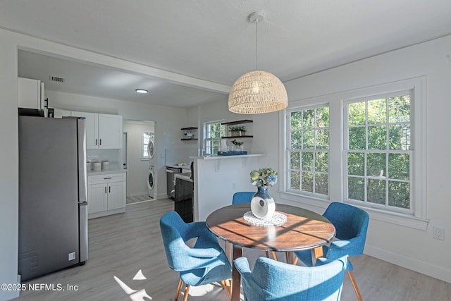 dining area featuring light wood-type flooring and stacked washer / dryer