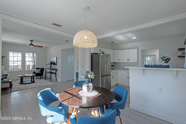 dining room with beamed ceiling, light hardwood / wood-style flooring, and ceiling fan with notable chandelier