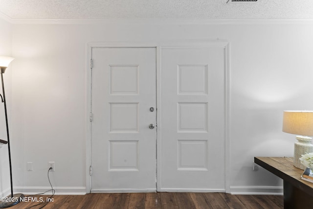 entrance foyer with a textured ceiling, dark wood-type flooring, and ornamental molding