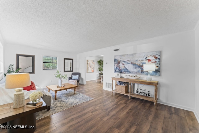 living room with a textured ceiling and dark hardwood / wood-style flooring