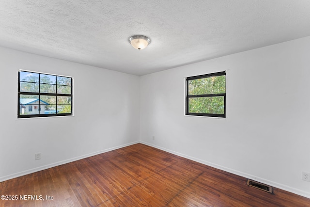 empty room featuring wood-type flooring and a textured ceiling