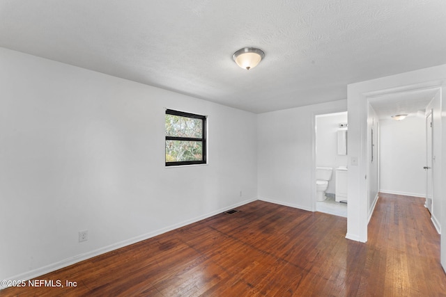 unfurnished room with a textured ceiling and dark hardwood / wood-style flooring