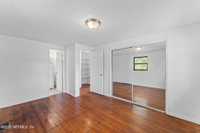 unfurnished bedroom with ensuite bath, a textured ceiling, and hardwood / wood-style floors