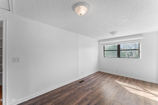 unfurnished room with a textured ceiling and dark wood-type flooring