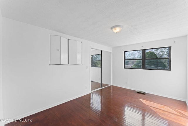 unfurnished bedroom with a textured ceiling, a closet, and hardwood / wood-style flooring