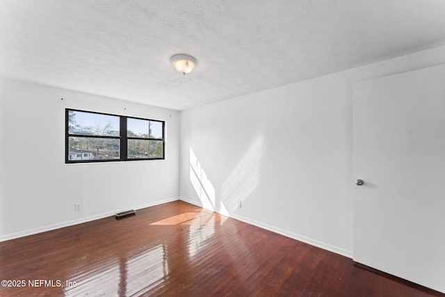 spare room with a textured ceiling and dark wood-type flooring