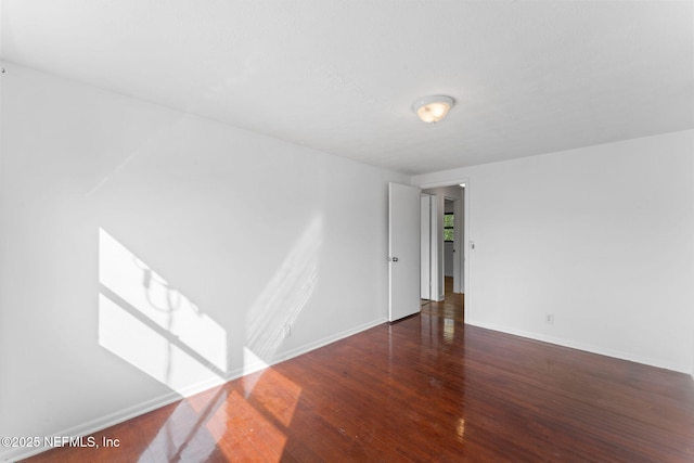 unfurnished room with dark wood-type flooring