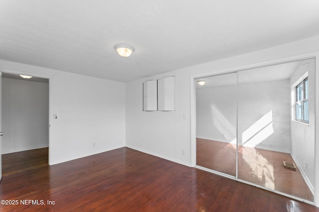 unfurnished bedroom featuring a closet and dark wood-type flooring