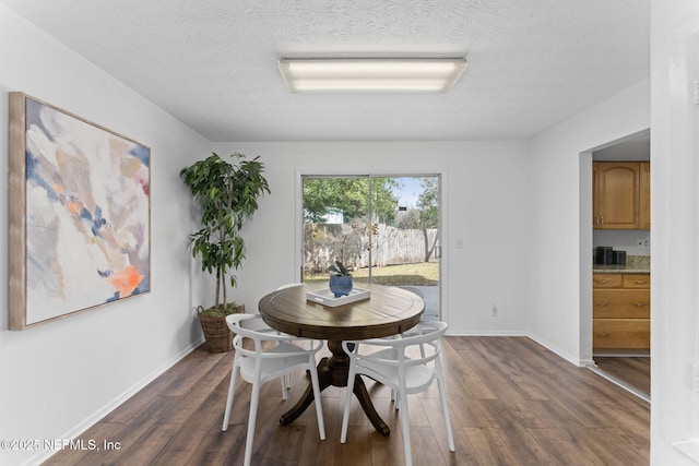 dining space featuring a textured ceiling and dark hardwood / wood-style flooring