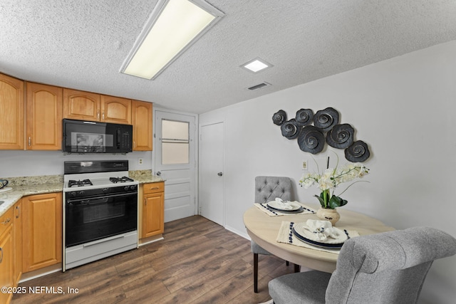 kitchen with gas range oven, light stone counters, a textured ceiling, and dark hardwood / wood-style floors