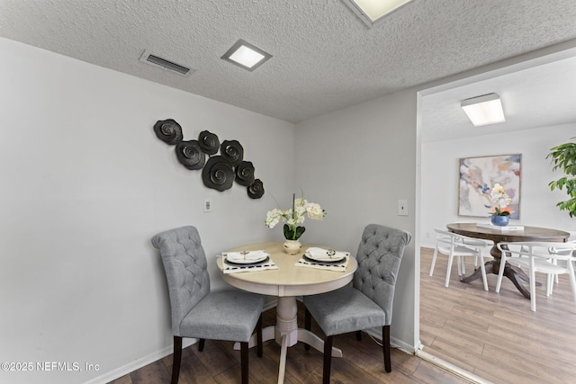 dining area featuring wood-type flooring and a textured ceiling