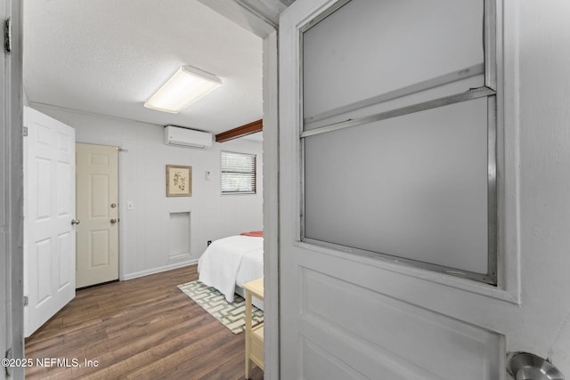 bedroom with dark wood-type flooring, a textured ceiling, and a wall mounted AC