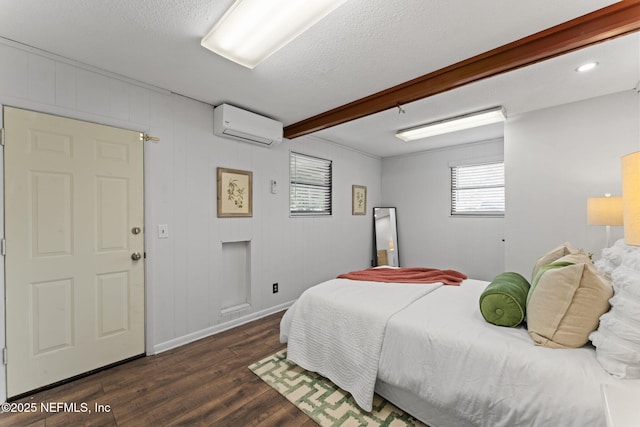 bedroom with a textured ceiling, dark hardwood / wood-style floors, a wall unit AC, and beamed ceiling