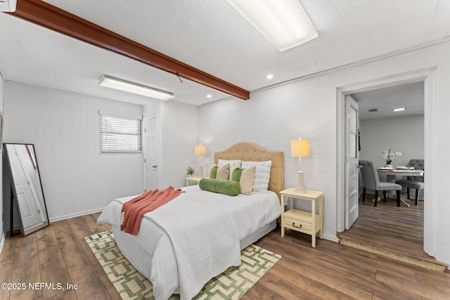 bedroom featuring beam ceiling, dark hardwood / wood-style flooring, and a textured ceiling