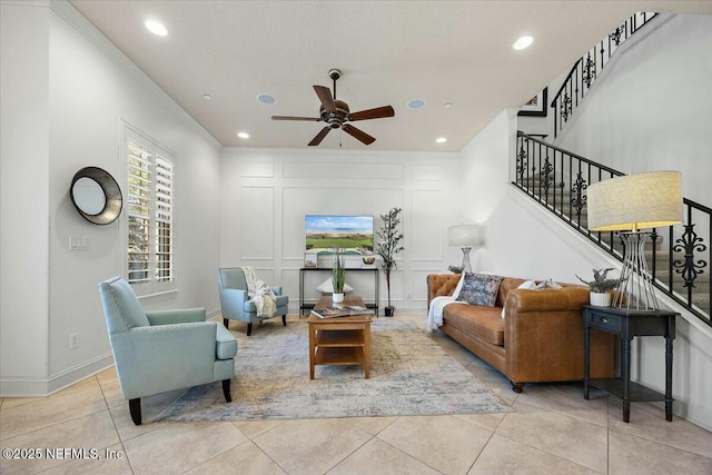 living room with light tile patterned floors, ornamental molding, and ceiling fan