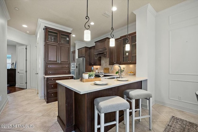 kitchen with a kitchen bar, sink, high end refrigerator, kitchen peninsula, and pendant lighting