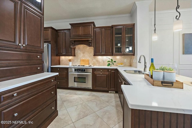 kitchen featuring crown molding, appliances with stainless steel finishes, sink, and decorative light fixtures