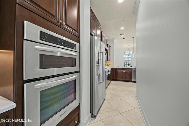 kitchen featuring light tile patterned floors, sink, hanging light fixtures, stainless steel appliances, and dark brown cabinetry