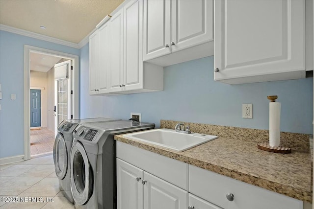 clothes washing area with sink, crown molding, washing machine and dryer, cabinets, and light tile patterned flooring