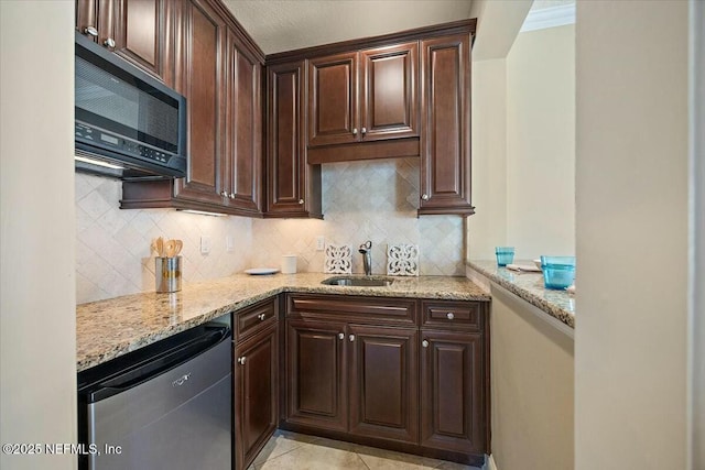 kitchen featuring dark brown cabinetry, sink, dishwasher, light stone countertops, and decorative backsplash