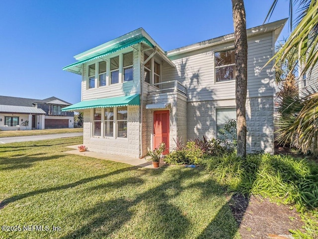 rear view of house featuring a lawn and a balcony