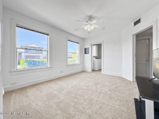 unfurnished bedroom featuring washer / dryer, light carpet, and ceiling fan