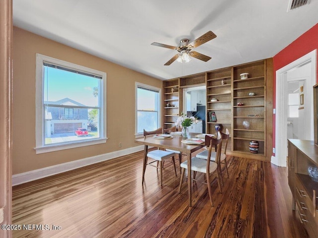 dining room with built in shelves, ceiling fan, and dark hardwood / wood-style flooring