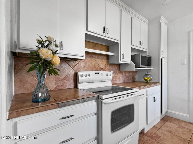 kitchen with tasteful backsplash, white cabinetry, light tile patterned floors, and white range with electric stovetop