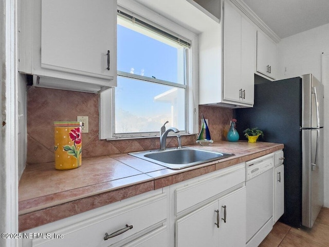 kitchen with sink, white cabinetry, tile counters, white dishwasher, and decorative backsplash