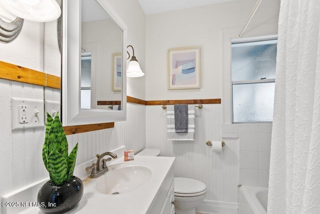 full bathroom with wainscoting, shower / tub combo with curtain, vanity, and toilet