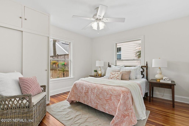 bedroom featuring light wood finished floors, multiple windows, baseboards, and a ceiling fan