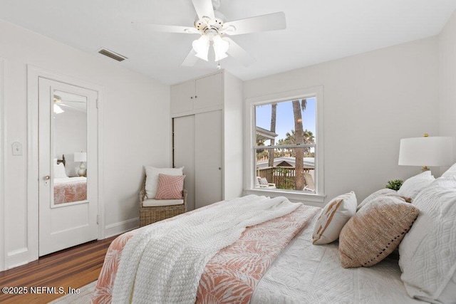 bedroom with a closet, visible vents, ceiling fan, wood finished floors, and baseboards