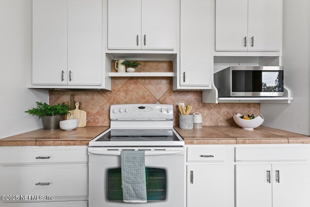 kitchen with tasteful backsplash, white cabinets, electric stove, stainless steel microwave, and light countertops