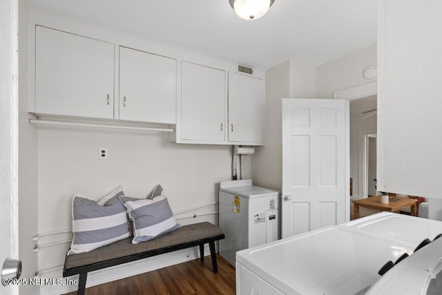 washroom with cabinet space, dark wood finished floors, visible vents, and washing machine and clothes dryer