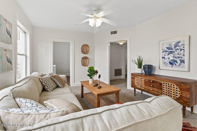 carpeted living area featuring baseboards, visible vents, and a ceiling fan